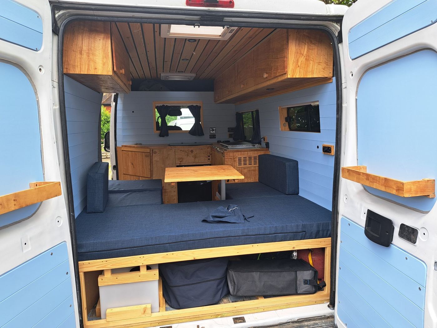 Finished campervan interior viewed through rear doors — custom carpentry