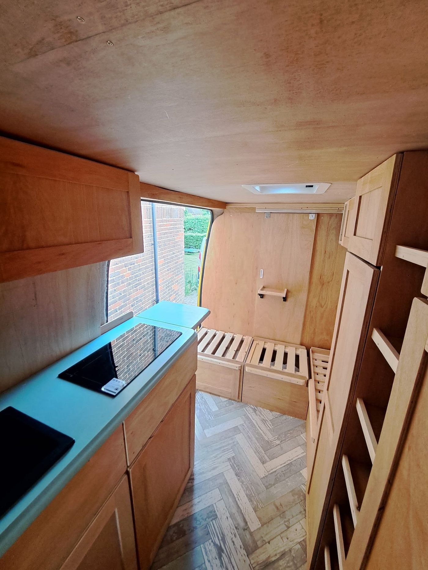Campervan kitchen carpentry with teal worktop and herringbone floor